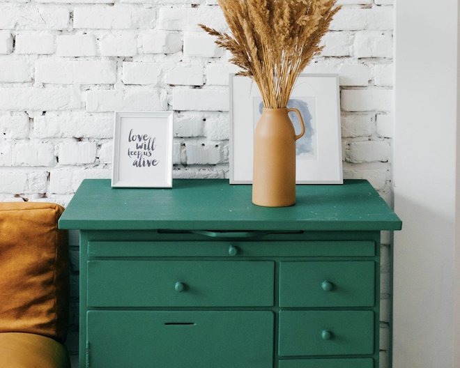 Some drawer table with a photo frame, jar and other items placed on it