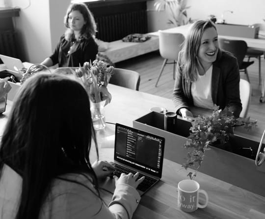 Some office staff including 3 women working on their laptops.