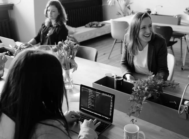 Some office staff including 3 women working on their laptops.